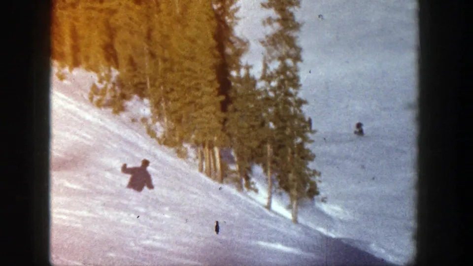 A wider Aspen ski-slope view shows one skier in the foreground and another distant figure on the snow near the trees.