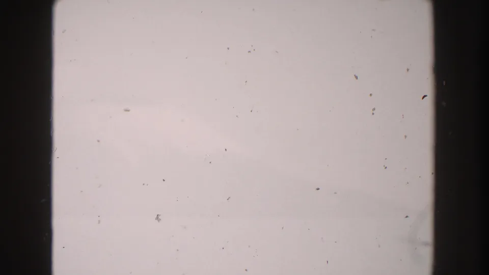 1960s Italy 8mm home-movie frame with a pale blank field, dark film edges, dust, and subtle exposure variation.
