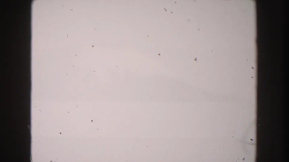 1960 Italy 8mm frame with a washed blank field, dark gate edge, small dust marks, and visible film wear.