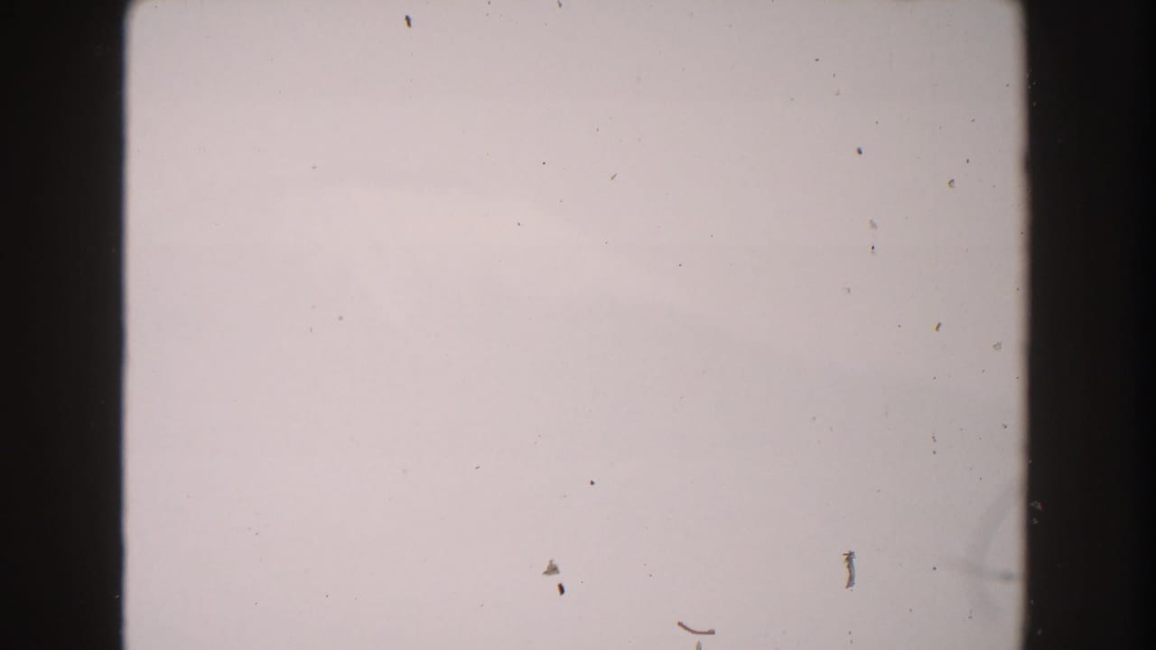 1960 Italy 8mm frame showing pale overexposed sky, dark film edges, and visible dust with no people or landmarks.