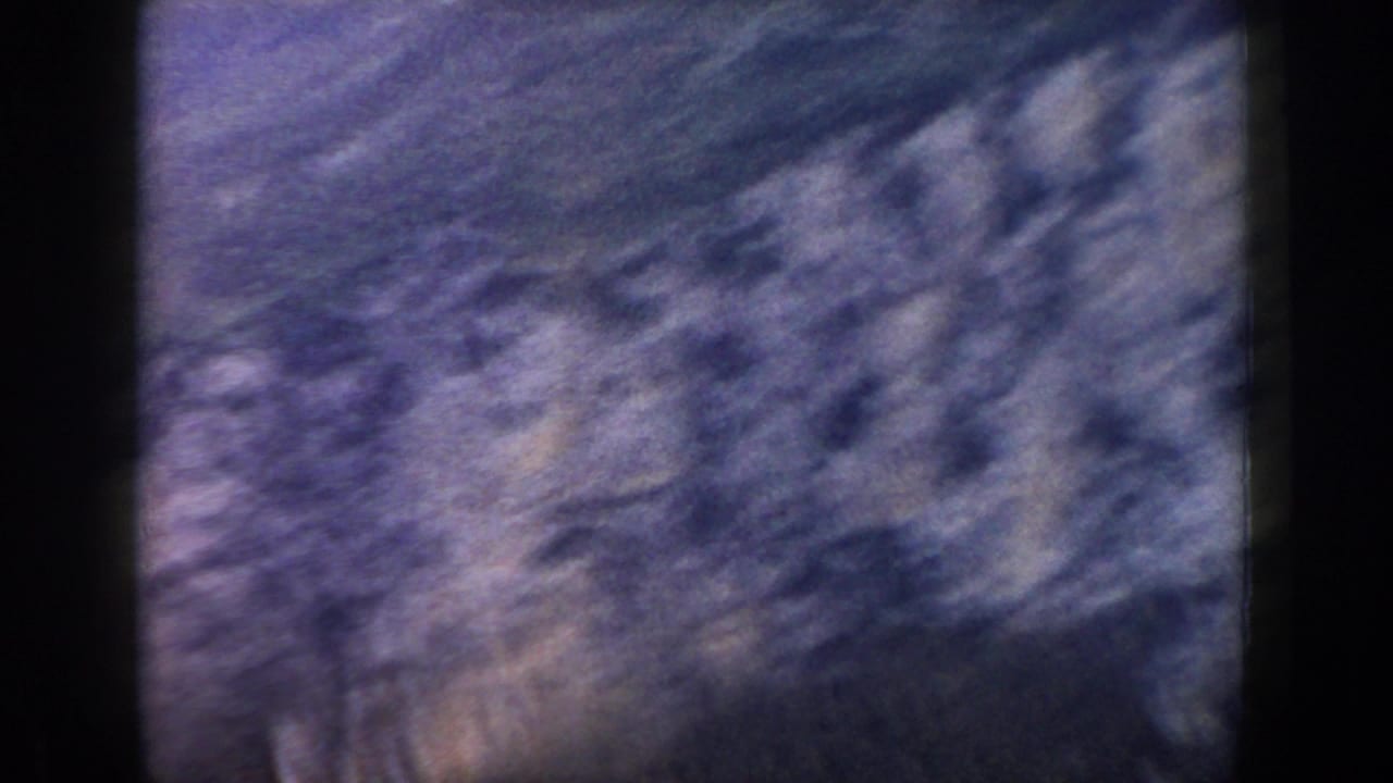 Blurred rocky terrain fills the frame with dark film edges.
