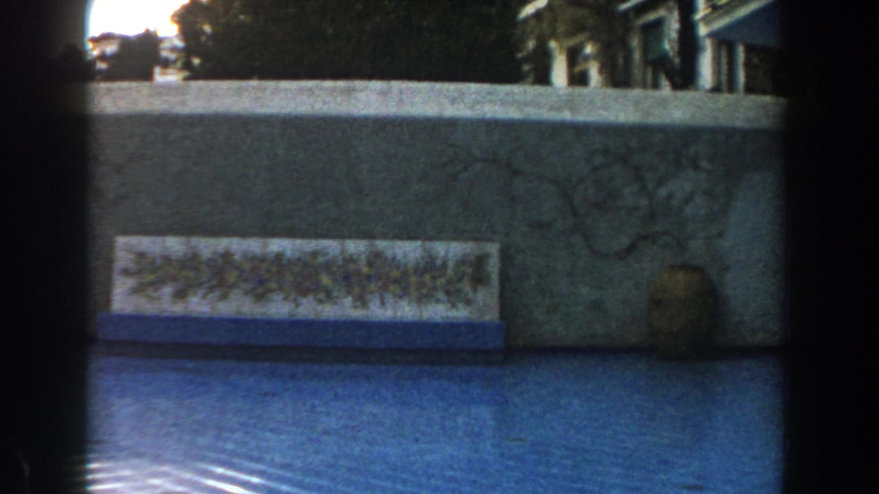 Textured courtyard wall with floral tile panel, blue-tiled surface, and earthenware jar.