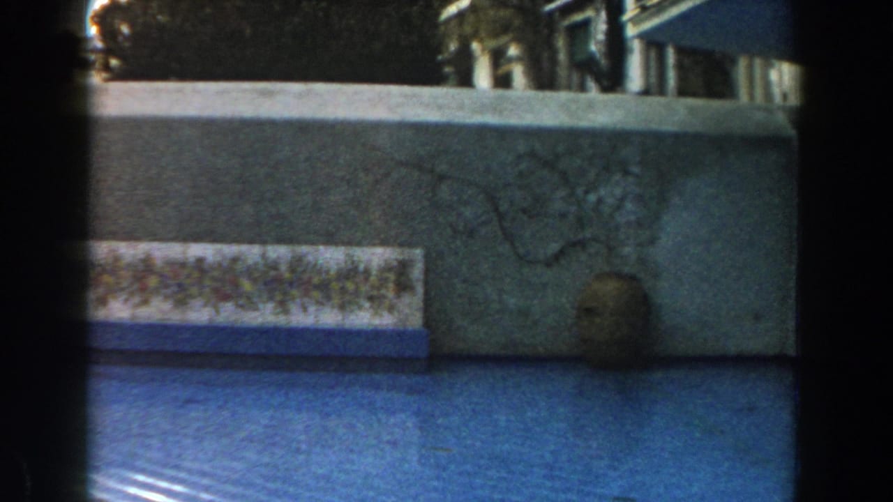Similar courtyard view with wall, decorative tile panel, blue surface, and jar.