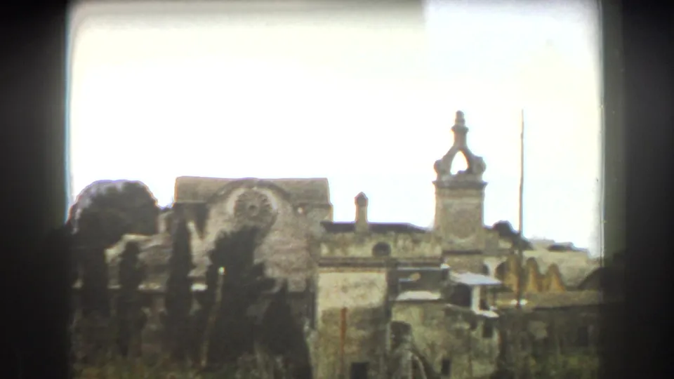 1960 Italy 8mm frame showing old stone religious architecture and an ornate tower detail.
