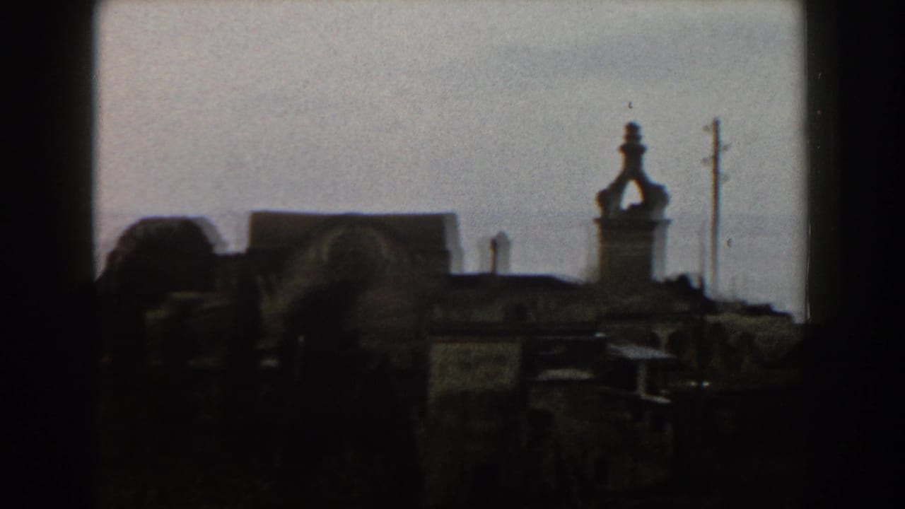 Dark rooftops and a tower silhouette above a coastal town skyline.