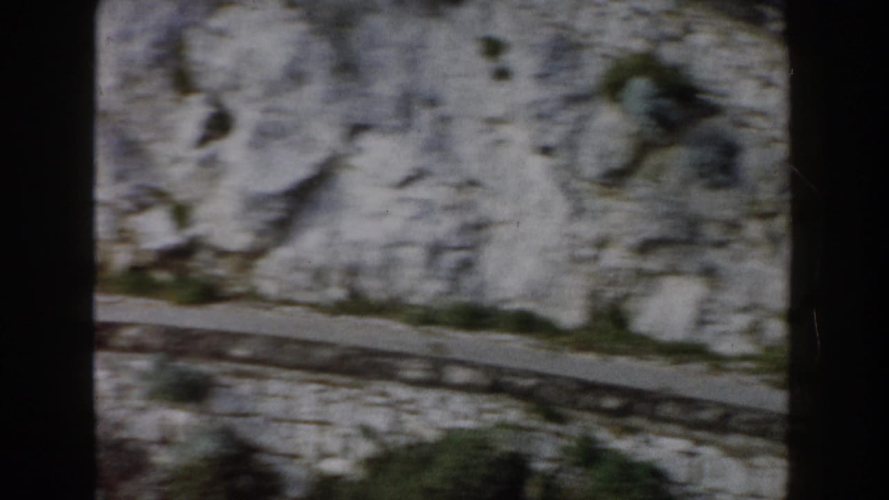 High view of a narrow road crossing pale rocky mountain terrain.