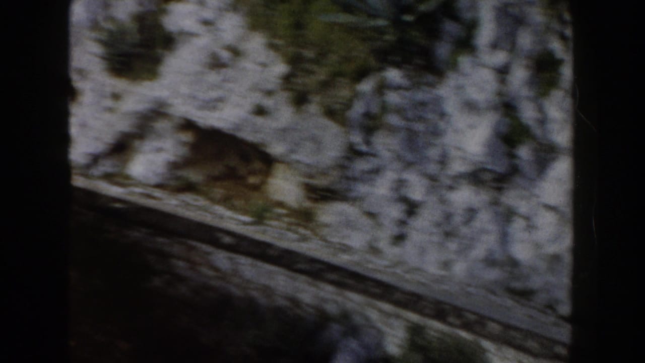 Rocky cliff face and curving road seen through dark frame borders.