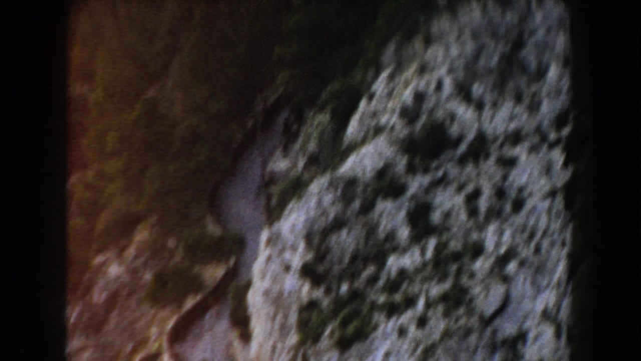 Close view of a rugged coastal cliff face with dark film edges.
