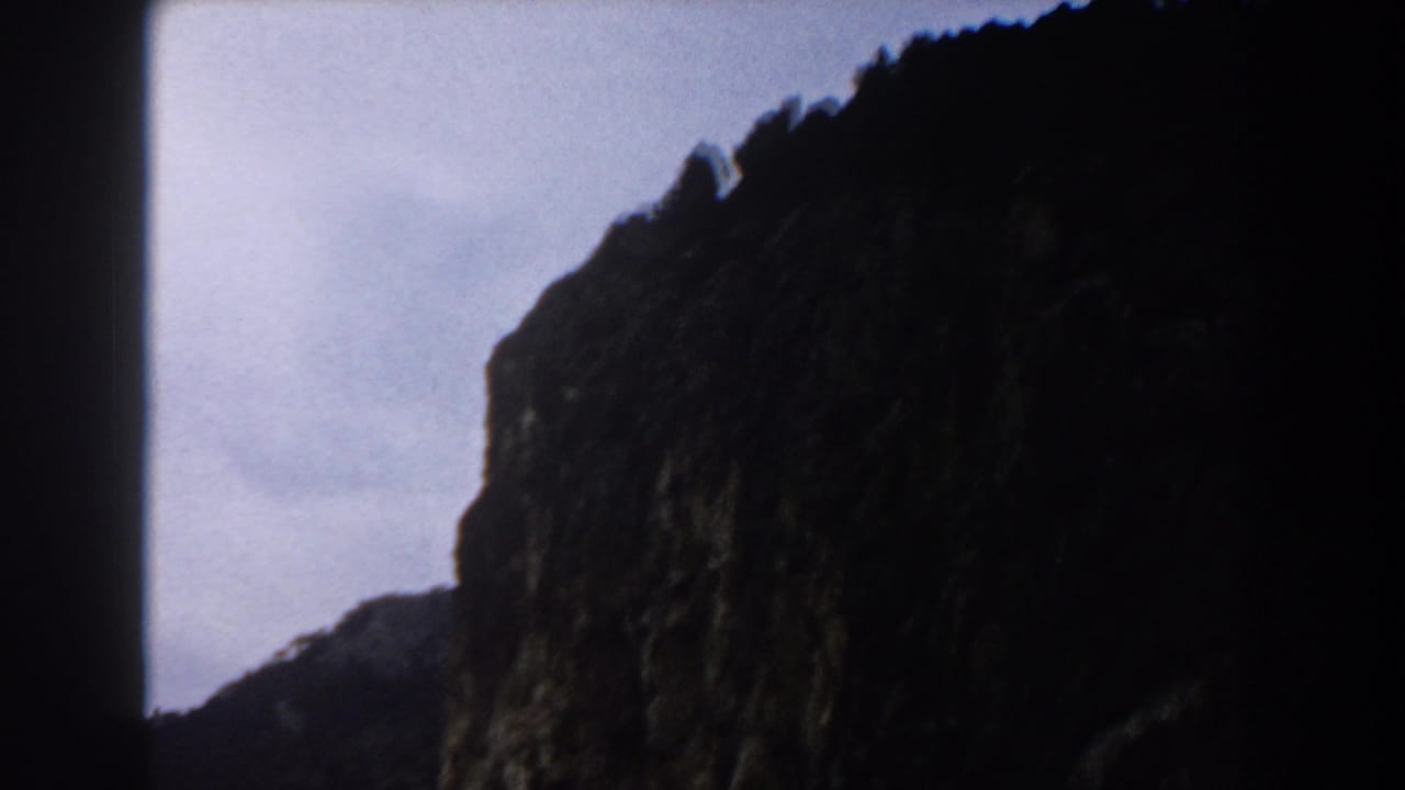 Dark rocky cliff silhouette below a pale sky.