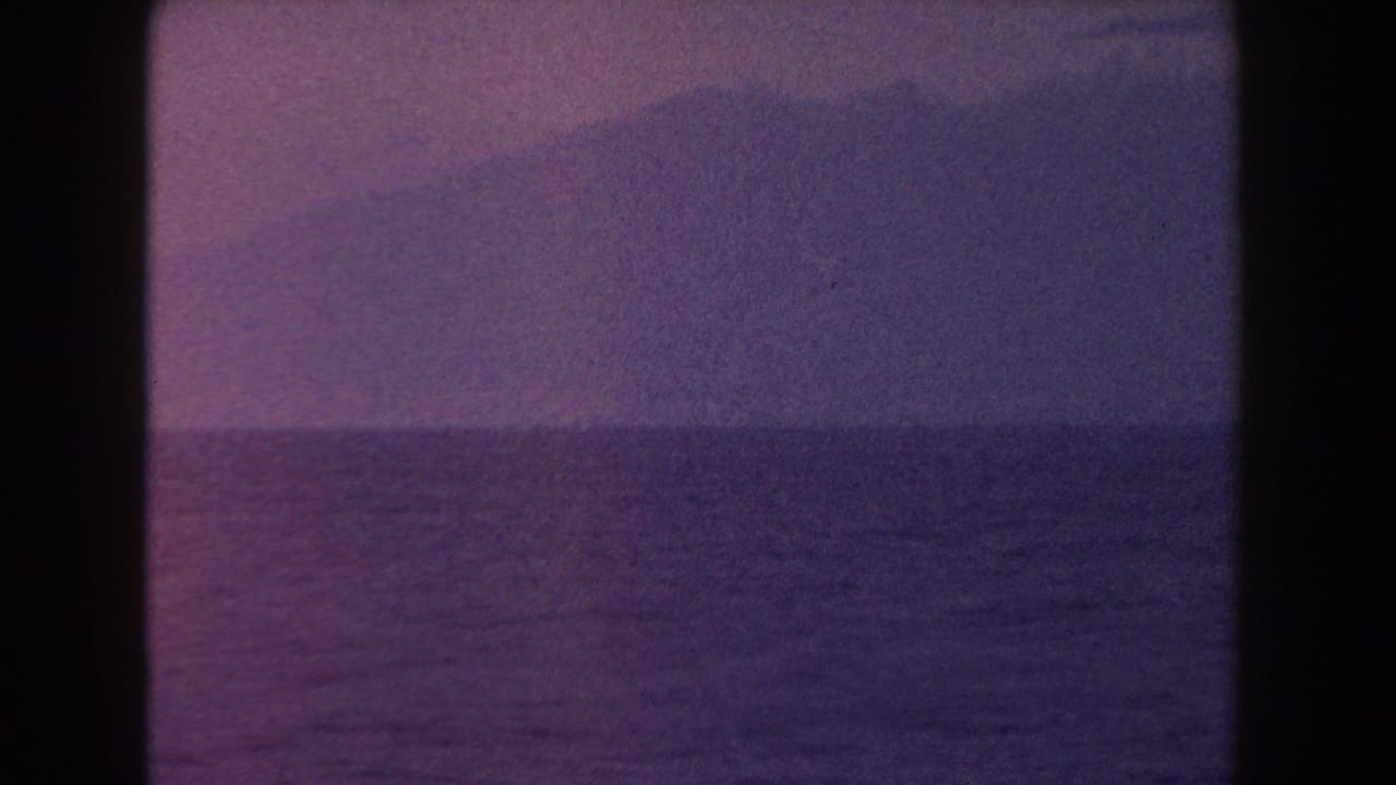 Purple ocean horizon with a shadowed mountain mass in the distance.