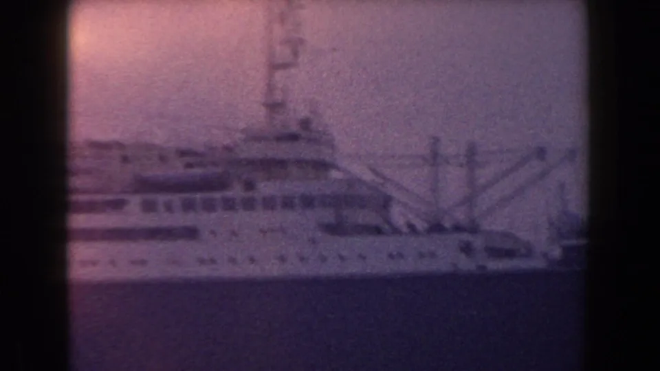 1960 Italian 8mm close view of a ship superstructure and mast, with water below and a warm haze over the frame.