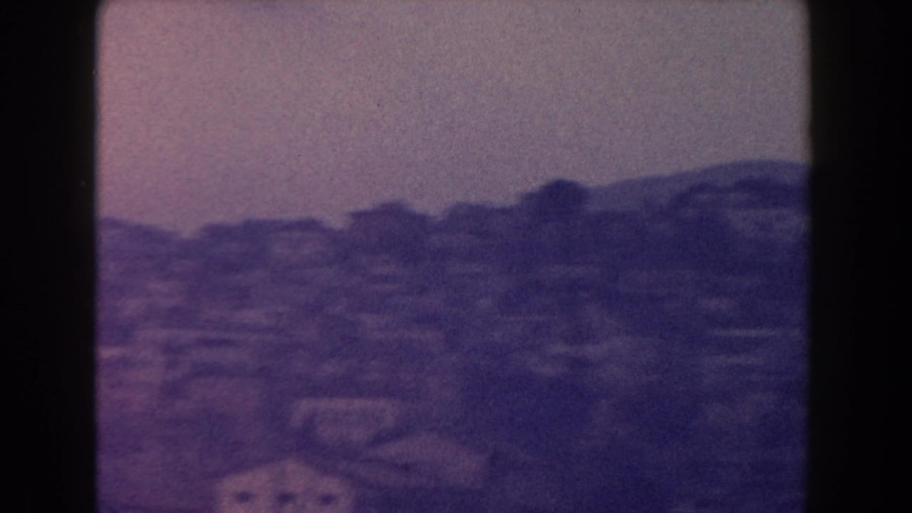 Distant hillside city under a hazy sky with dark 8mm frame edges.