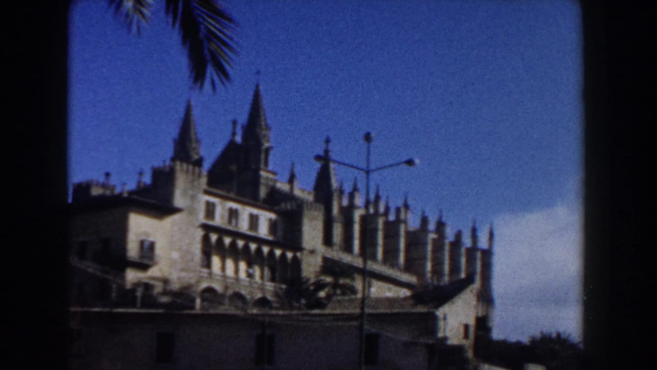 Cathedral facade and spires framed by dark window edges, with street lamps below.