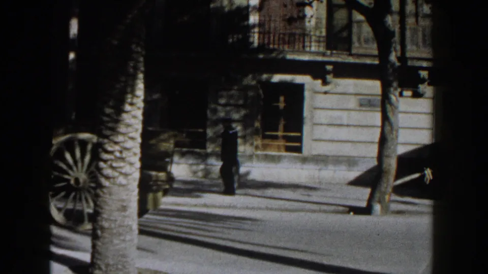 As the horse-drawn wagon leaves the frame, a pedestrian and building windows remain visible on the Italian street.