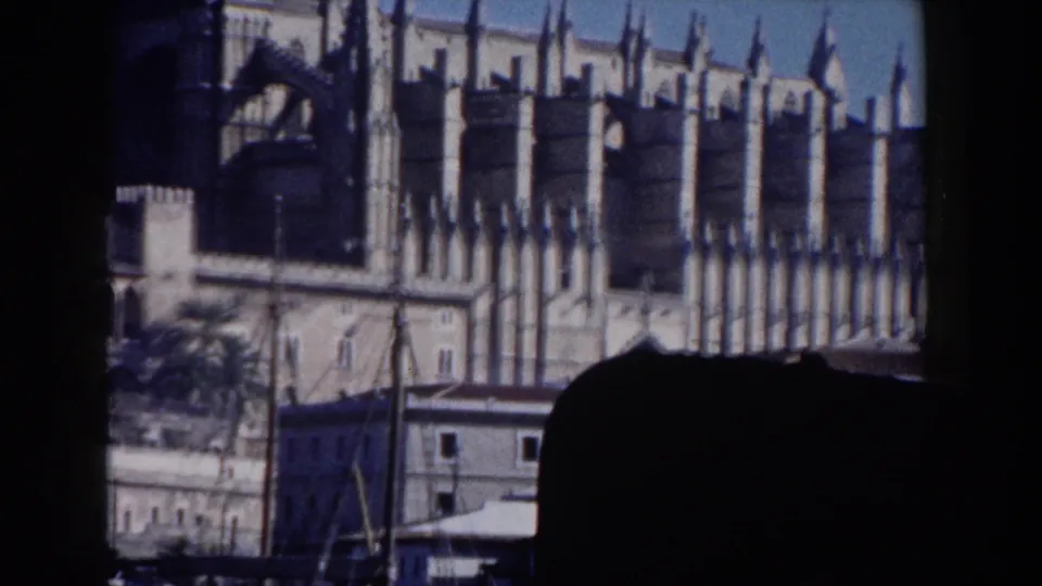 1960 Italy 8mm frame with a closer Gothic cathedral facade, pointed spires, arched details, and a dark foreground silhouette at bottom.