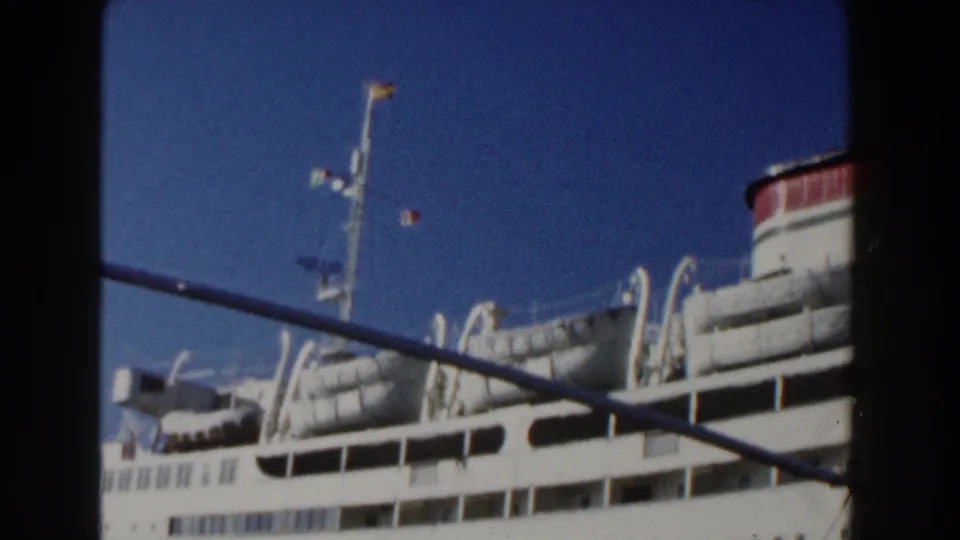 1960 Italy 8mm frame near the end of the pan, showing ship railings, lifeboats, mast, blue sky, and part of the red-topped funnel.