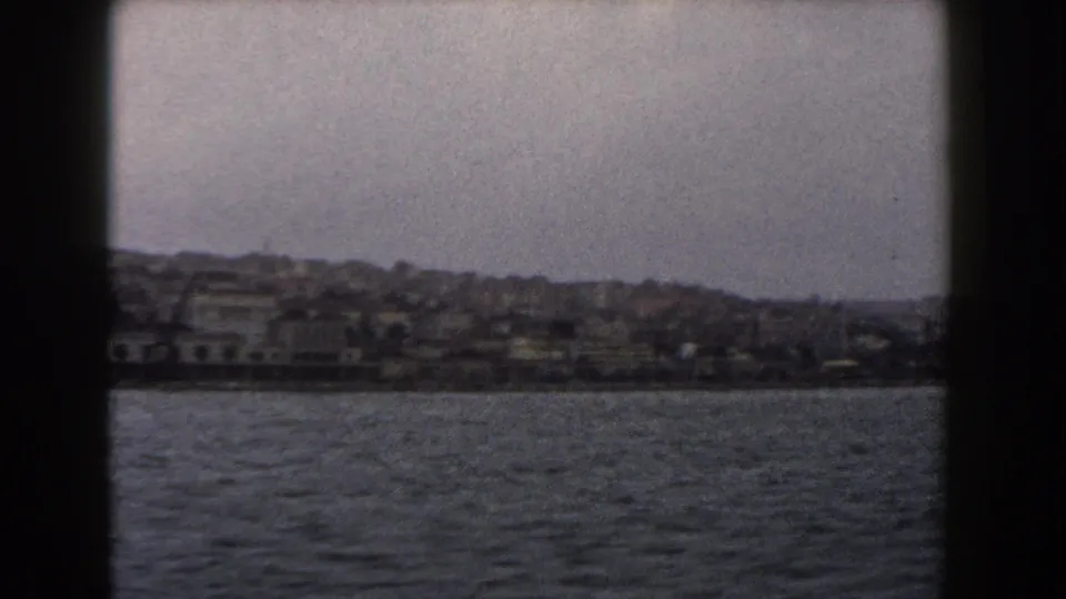 The final frame shows the Italian waterfront receding across the water, framed by dark porthole or window edges.