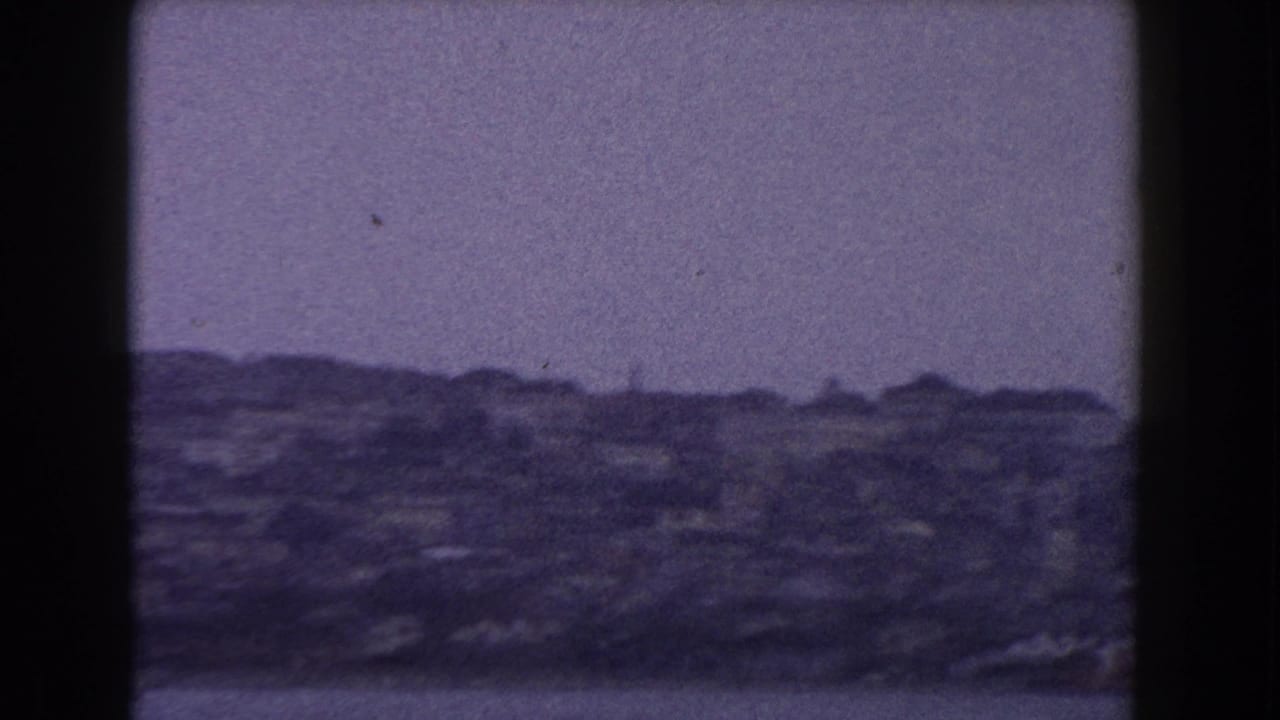 1960 8mm Italy travel view showing a soft, distant cityscape across water under a muted overcast sky.