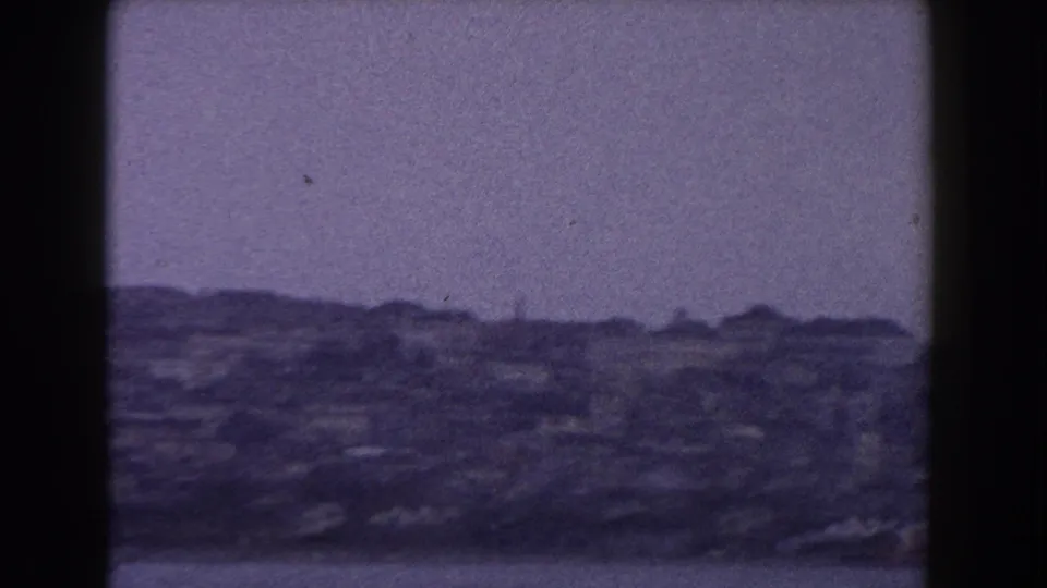 1960 8mm Italy travel view showing a soft, distant cityscape across water under a muted overcast sky.