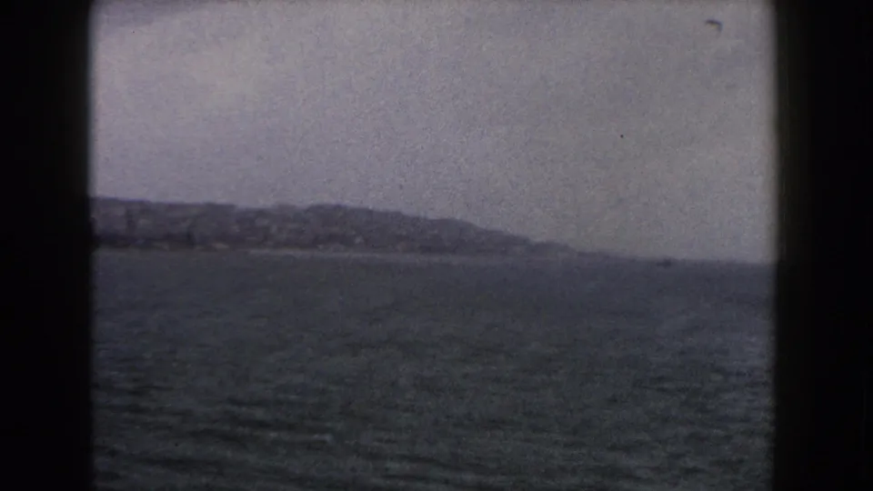 A late frame from the 1960 Italy 8mm clip shows open sea and a clearer distant shoreline with low hills.
