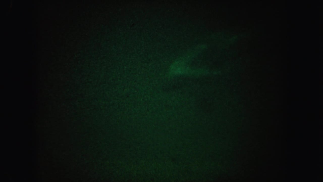 1962 California 8mm frame showing a faint greenish glow in a mostly dark, grainy field.