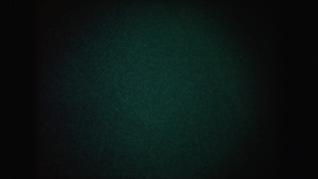 1962 California 8mm frame showing mostly darkness with greenish grain, vignetting, and a dim hazy light patch.