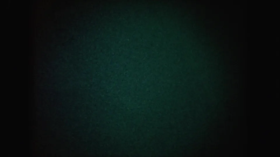 1962 California 8mm frame showing mostly darkness with greenish grain, vignetting, and a dim hazy light patch.