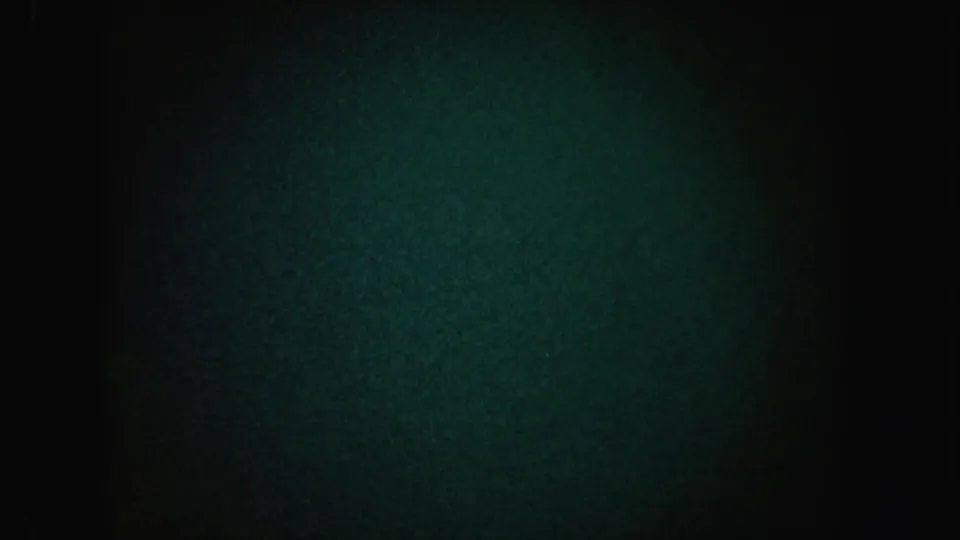Dark 8mm home-movie frame from the 1962 California clip, with a muted green cast and indistinct central light.