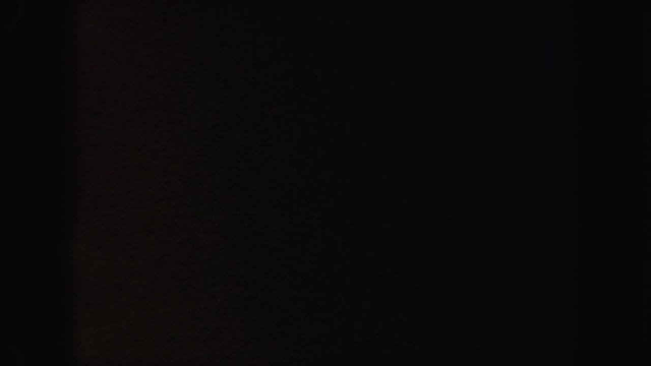 Very dark frame with a faint reddish-brown vertical area and minimal visible detail.