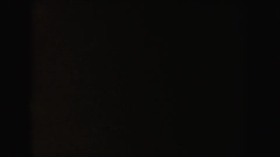 Dark 1962 California 8mm frame with a faint reddish-brown exposed area and surrounding blackness, with no clear subject visible.