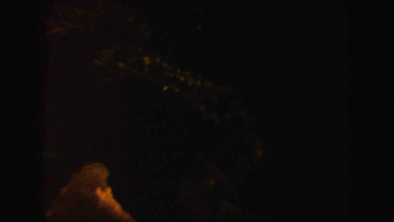 1962 California 8mm frame showing a dim underwater or aquarium scene with a faint amber coral-like form in deep shadow.