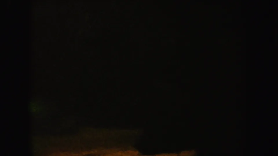 Low-exposure 1962 California 8mm frame where only a faint green band and dark underwater enclosure edges are visible.
