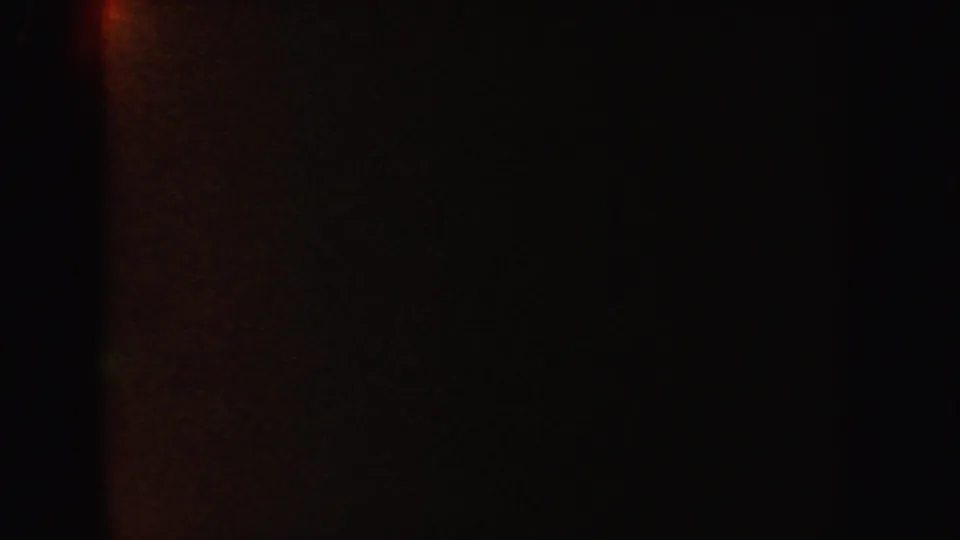 A mostly underlit 8mm frame from the 1962 California clip shows faint reddish-brown glow and shadowed cave-like surfaces.