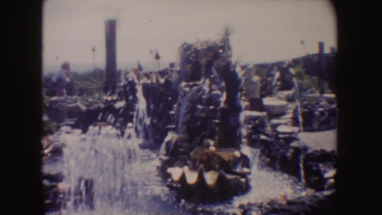 1962 California home-movie frame showing a rocky coastal garden with plants, a water feature, and bright sun exposure.