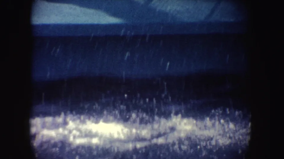 1962 California 8mm frame with foamy splash across dark blue pool water, softened by grain, scratches, and gate-edge darkness.