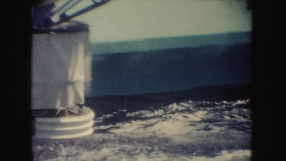 Soft 8mm view of a pale pool edge with splashing water during a California aquatic show sequence.