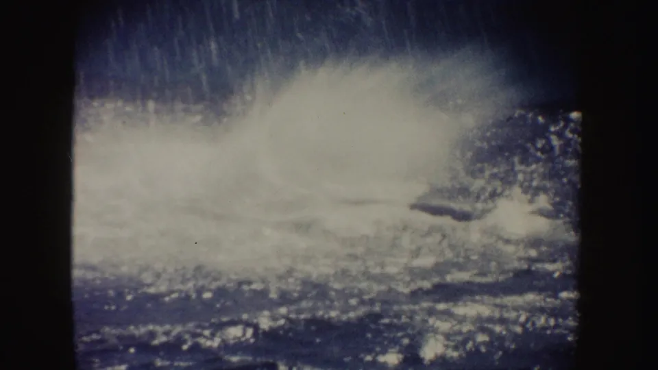A broad splash spreads over the ocean surface in the 1962 California 8mm clip, with the whale mostly hidden by spray.