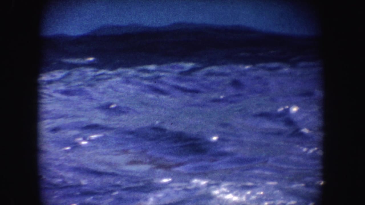 1962 California 8mm frame showing rippled blue show-pool water bordered by dark film edges, with no people visible.