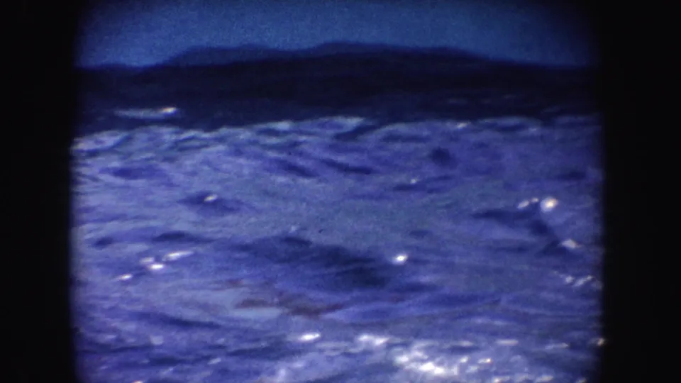 1962 California 8mm frame showing rippled blue show-pool water bordered by dark film edges, with no people visible.
