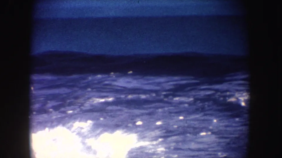 A blue-lit show pool surface in California footage, with bright water glare and heavy dark borders from the 8mm frame.