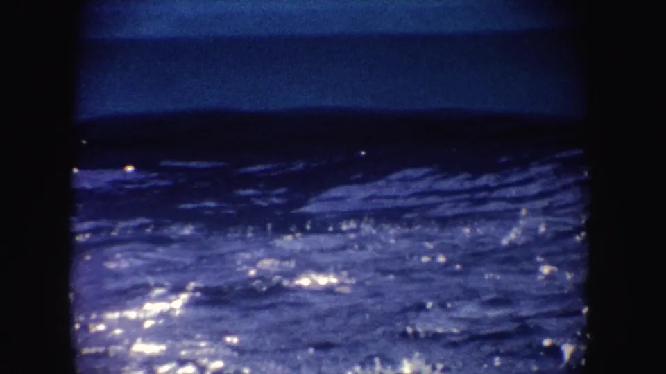 A visitor-shot 8mm view of shimmering show-pool water, with strong blue exposure and dark framing around the scene.