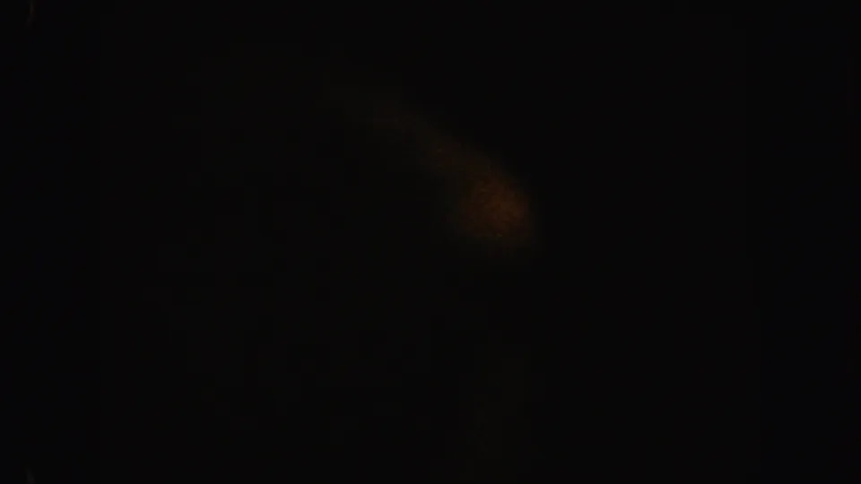 Dark 1962 California 8mm frame with a faint orange light speck, grain, and soft shadowed texture.