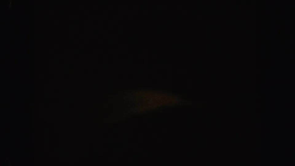 1962 California 8mm frame dominated by darkness, with a vertical frame boundary and a weak warm haze near the upper right.