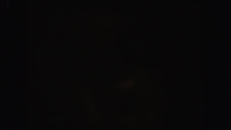 1962 California 8mm frame showing darkness with a dim amber glow, grain, and slight mottling across the film surface.