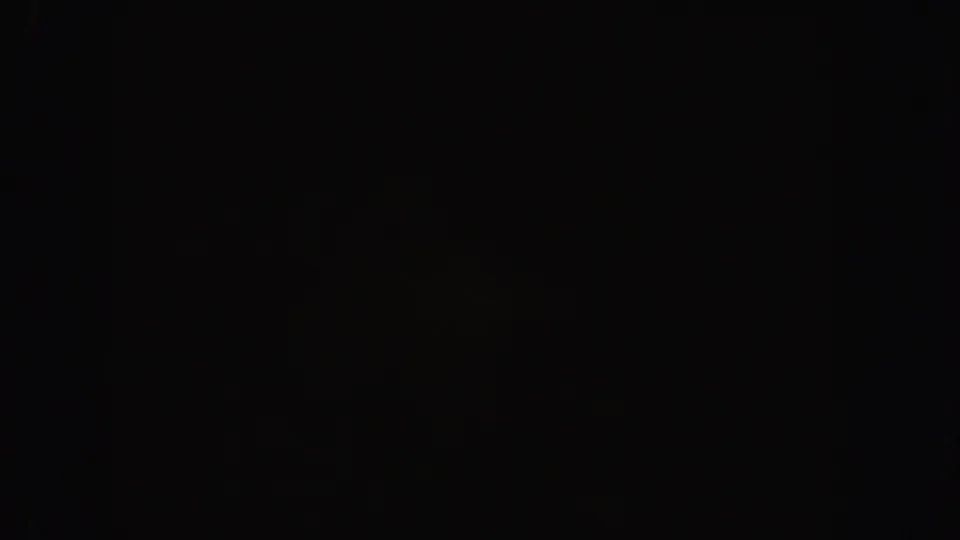 Underexposed 1962 California 8mm frame with faint, indistinct shapes in darkness and heavy grain.
