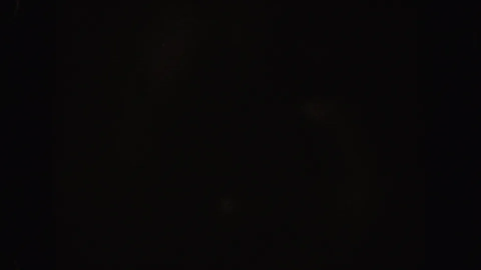 Dark 8mm home-movie frame from the 1962 California clip, with indistinct forms and visible grain.