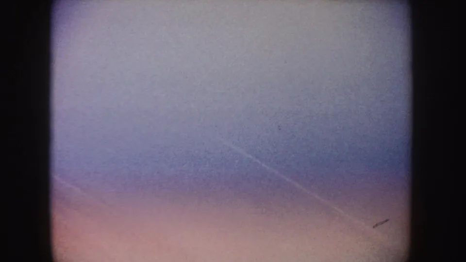 Soft 1962 home-movie frame with a pale poolside area and faint water edge, likely during a quick handheld camera movement.