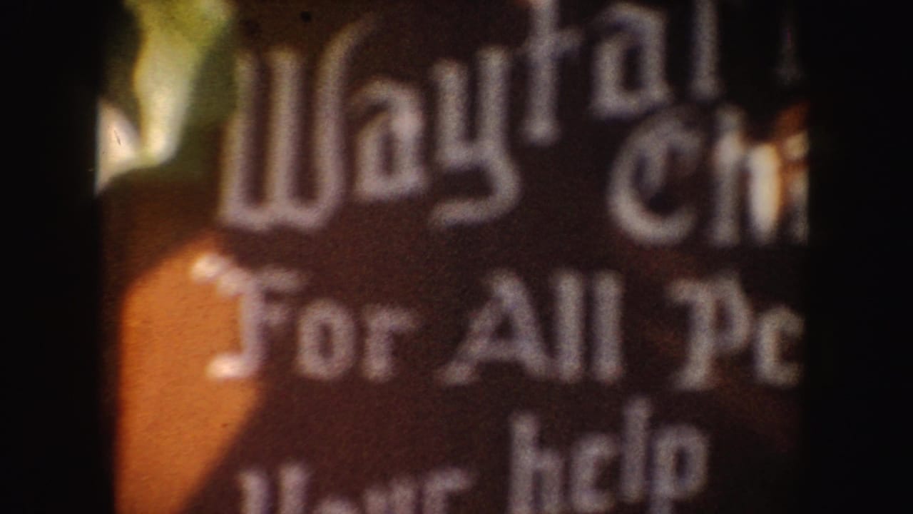 Blurred close-up of a dark sign with partial Wayfarer and For All People lettering.