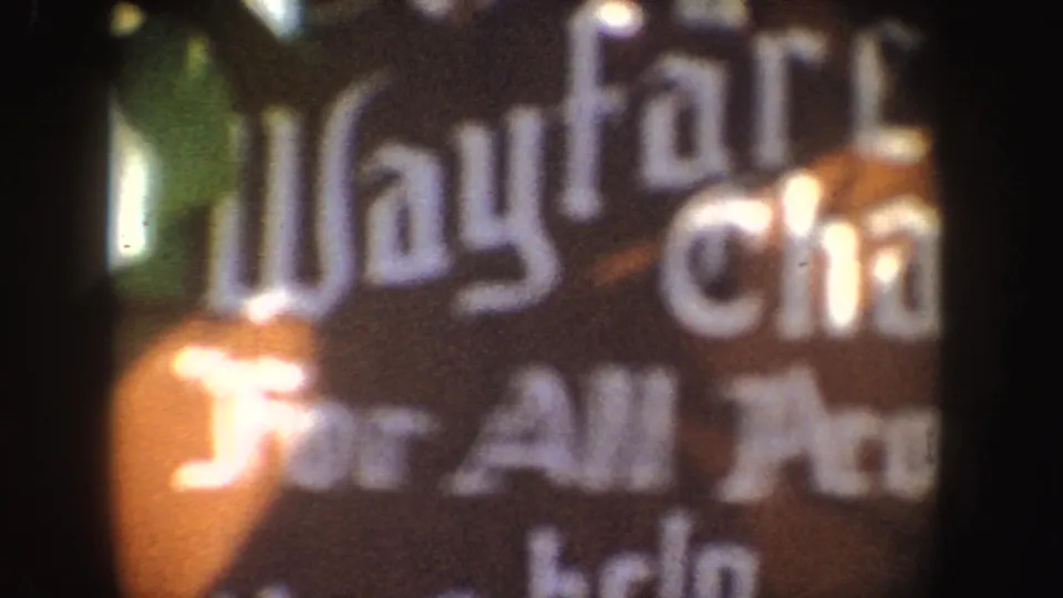 Soft 8mm close-up of the dark sign, with large partial Wayfarer letters and incomplete For All People wording visible.