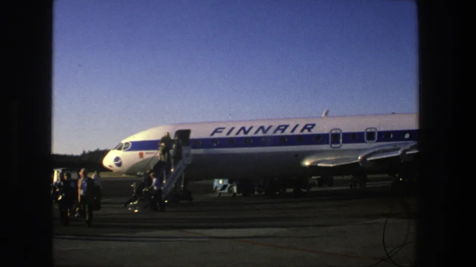 A Finnair airliner fills the frame as people stand near the mobile stairs on the Stockholm airport tarmac.
